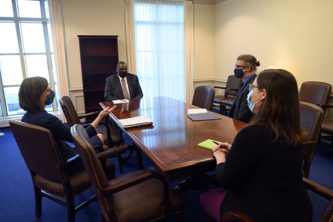 Four people sit at a conference table.