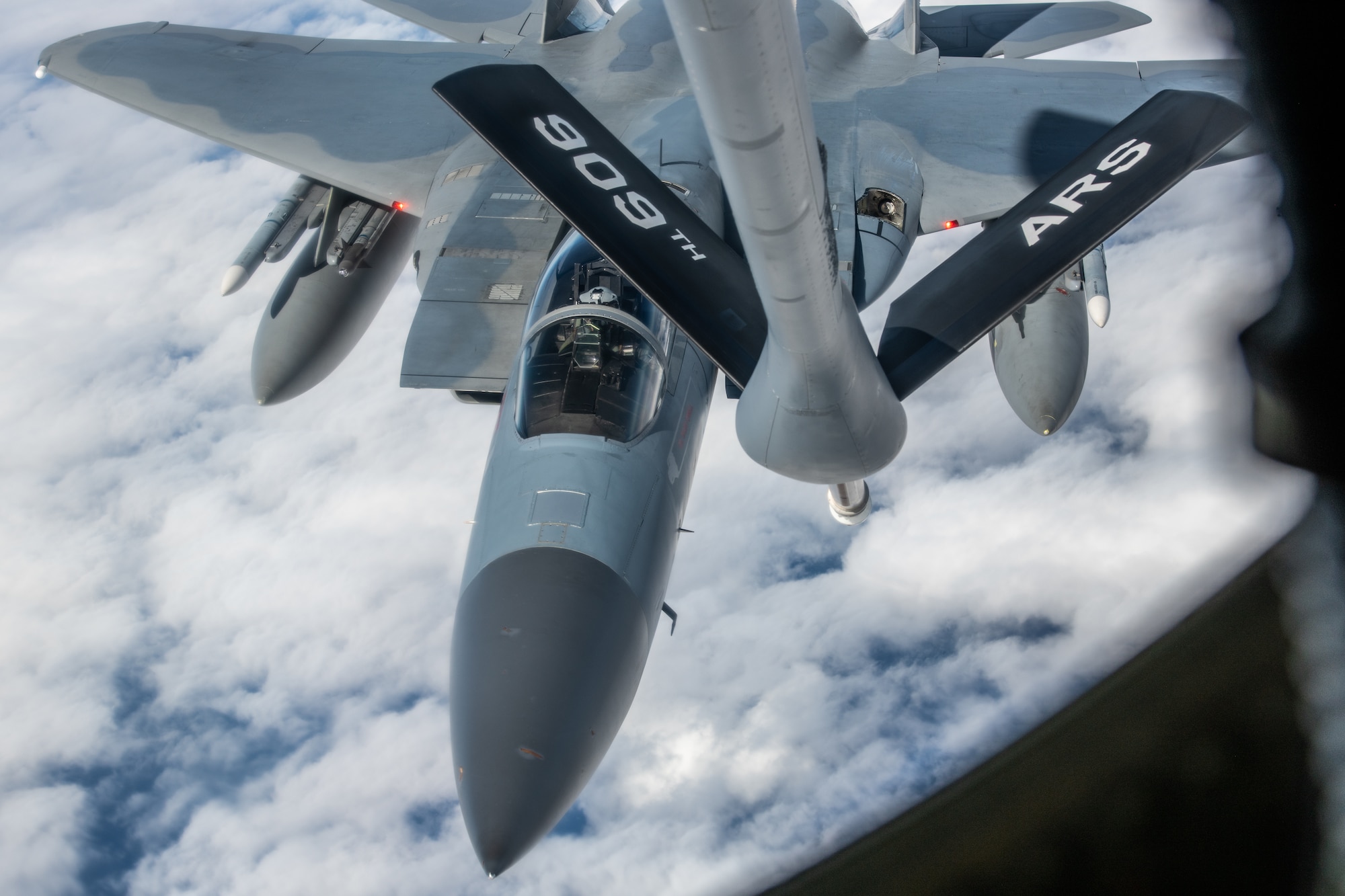 A fighter jet approaches the boom of a KC-135 as it gets ready to refuel
