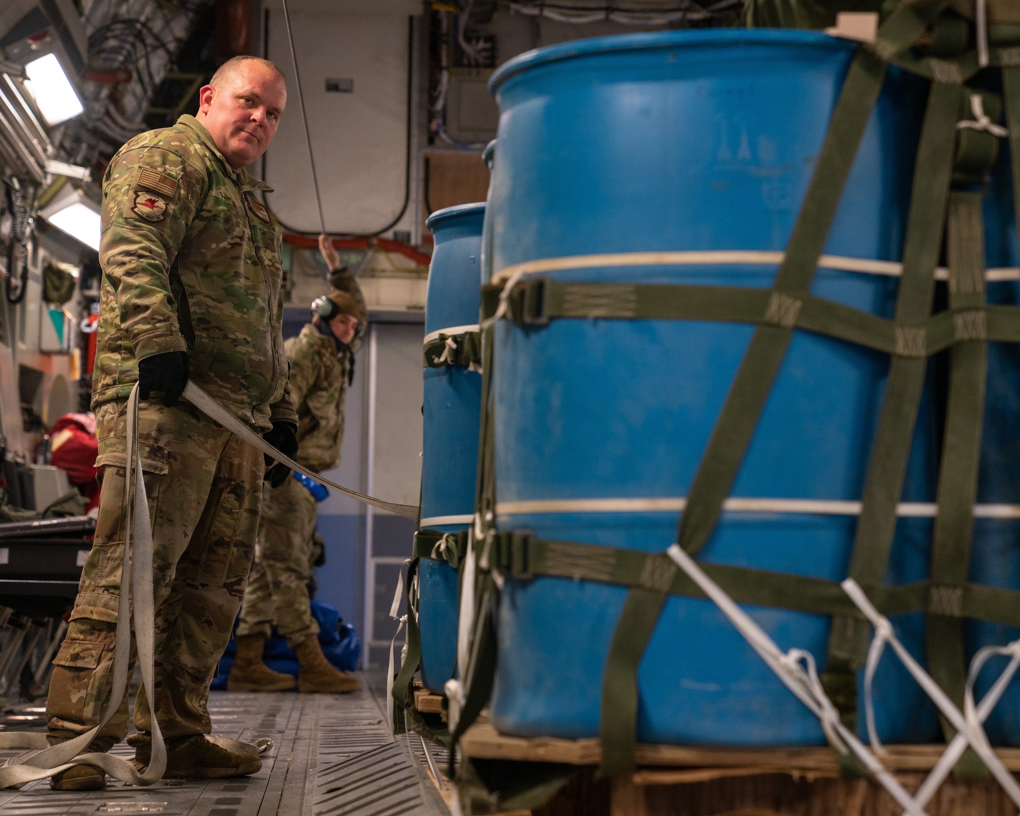 U.S. Air Force Senior Master Sgt. Douglass MacGregor, the 517th Airlift Squadron superintendent, secures a cargo pallet to a C-17 Globemaster III.