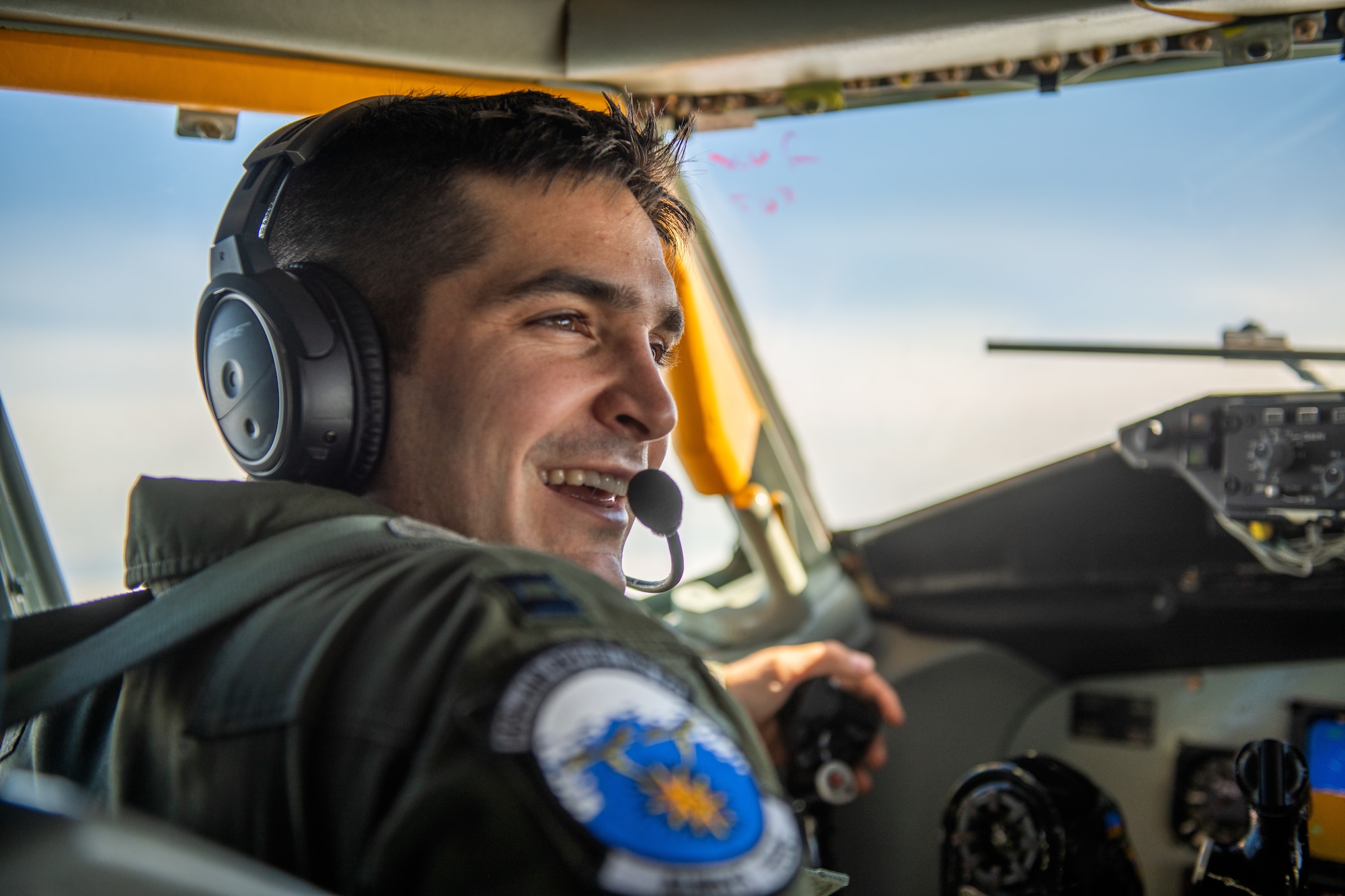 A pilot smiles as the cockpit glows from sunlight coming in