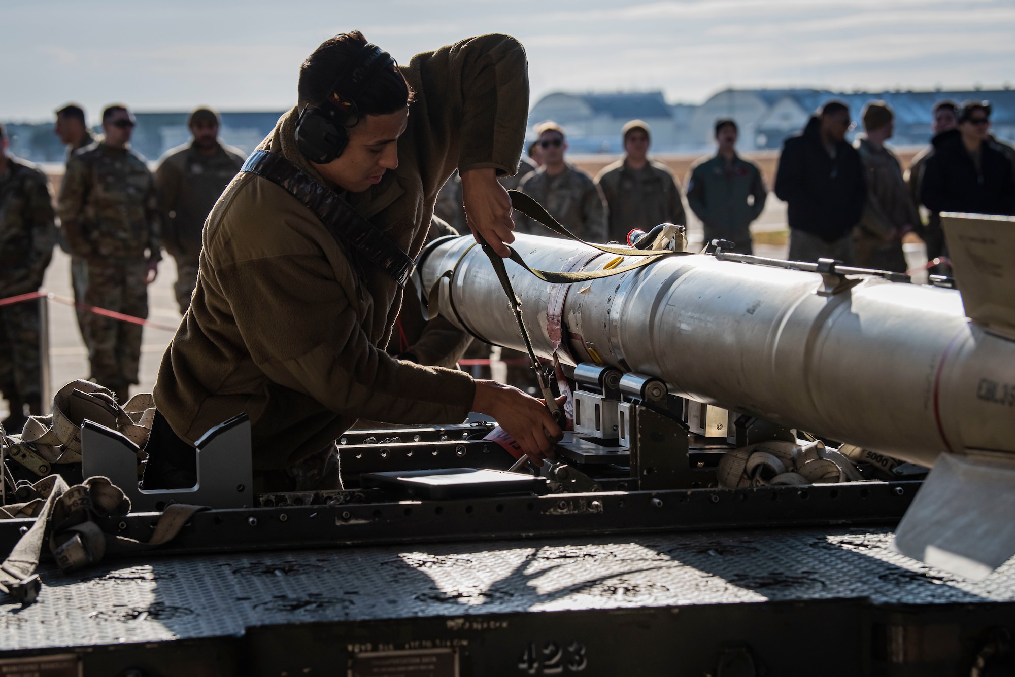 Man in military uniform ties down a missile.
