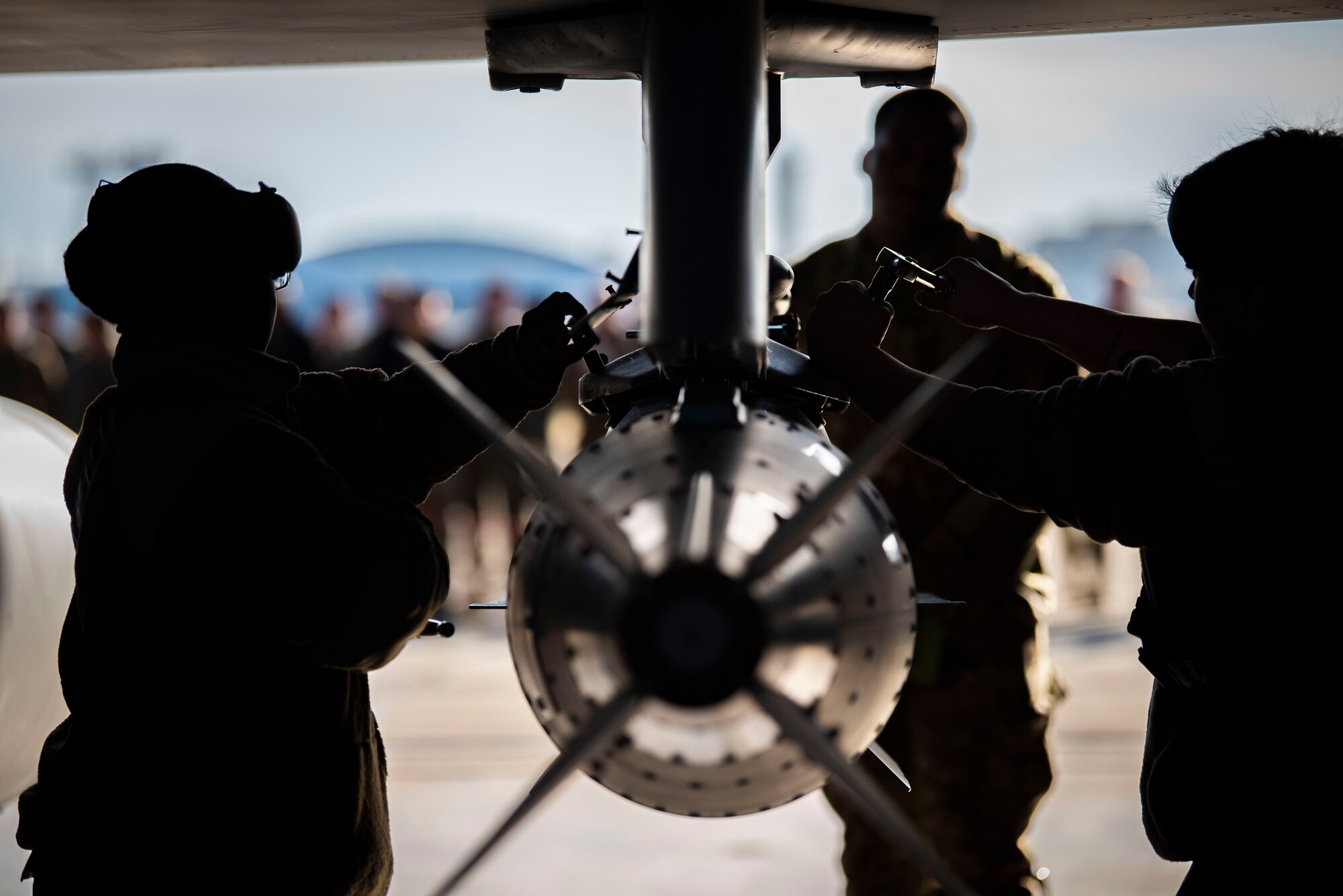 Woman and man in military uniform tightens screws on an F-16 with a tool.
