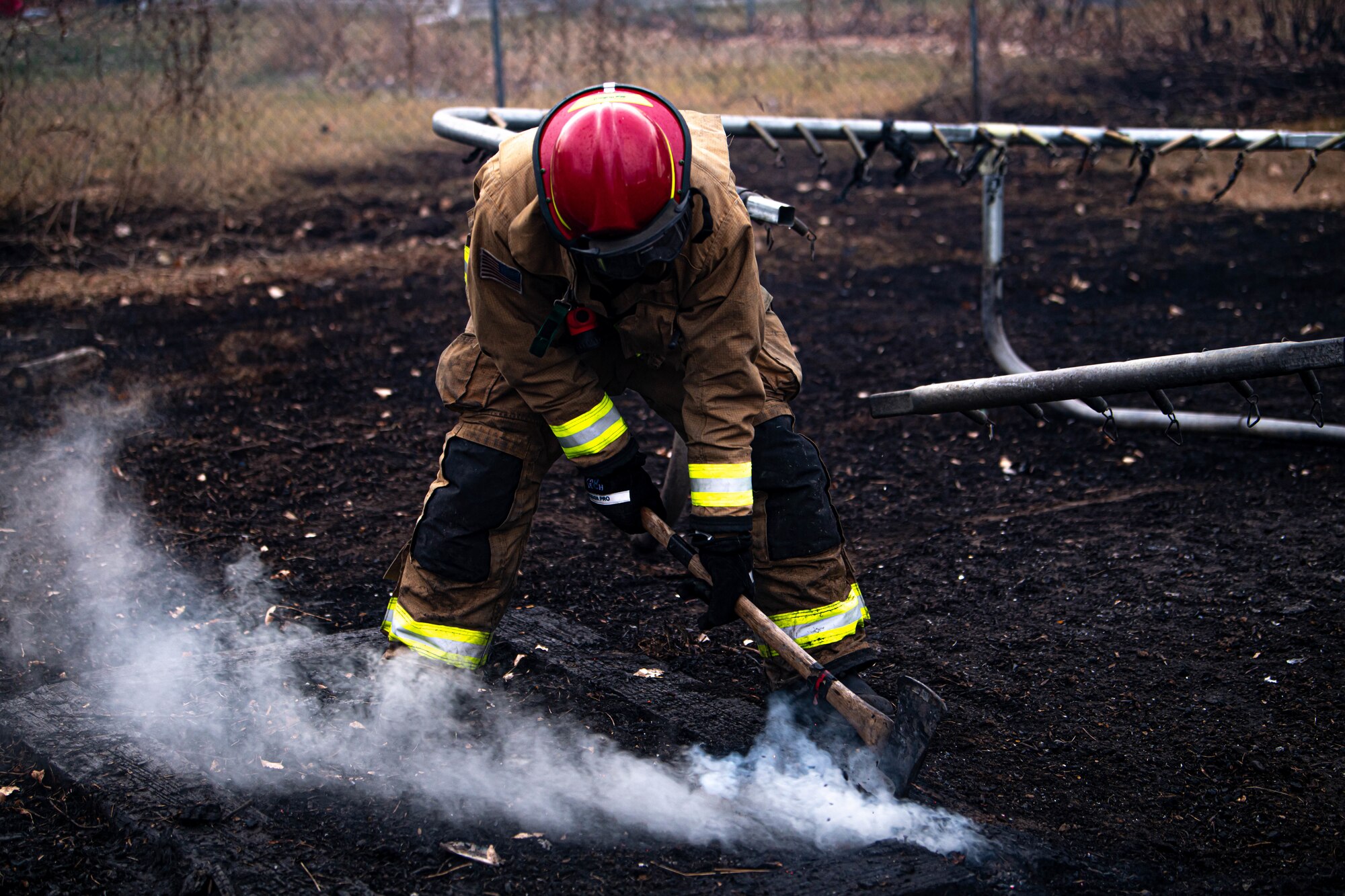 Staff Sgt. James Willett, 341st Civil Engineer Squadron firefighter, uses an ax to prevent embers from re-sparking during the Gibson Flats fire Dec. 1, 2021 in Great Falls, Montana.