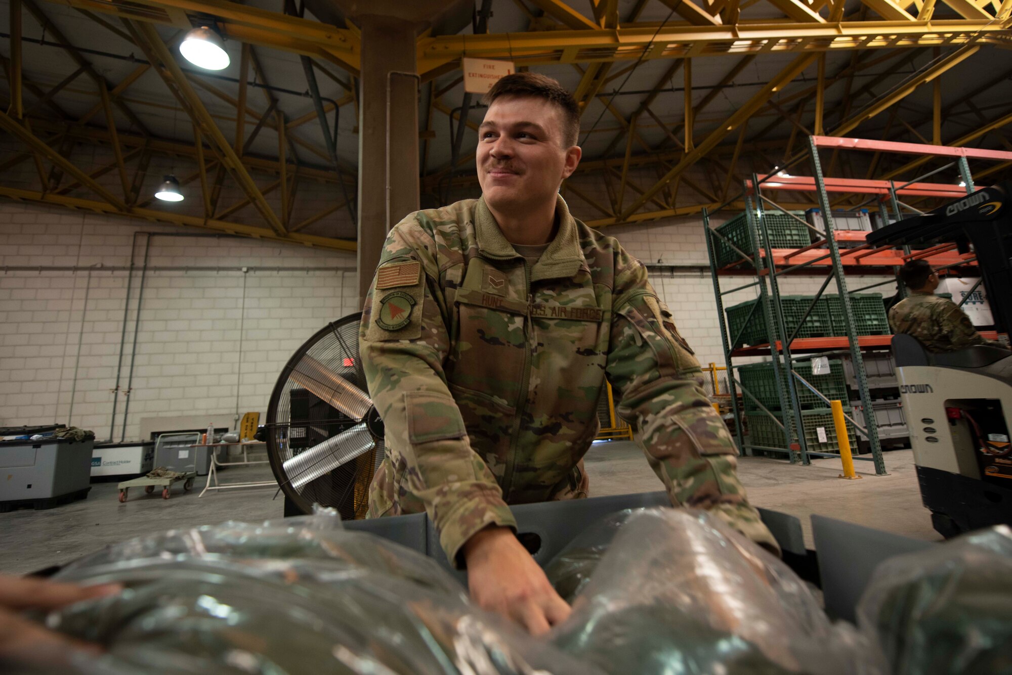 A man smiles while placing a package in a box.