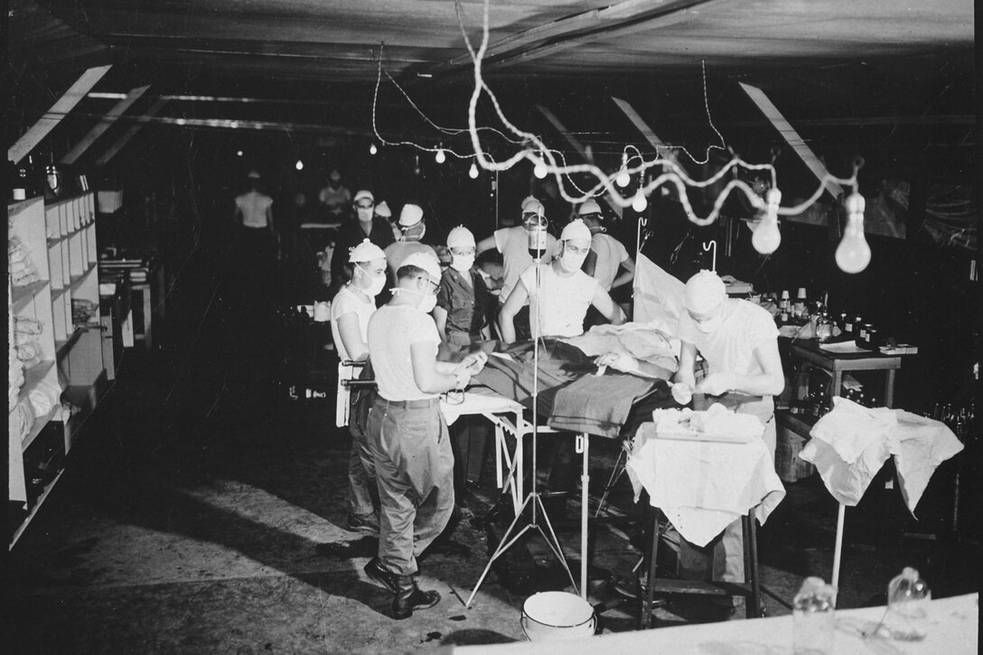 Medical personnel perform surgery inside a tent.
