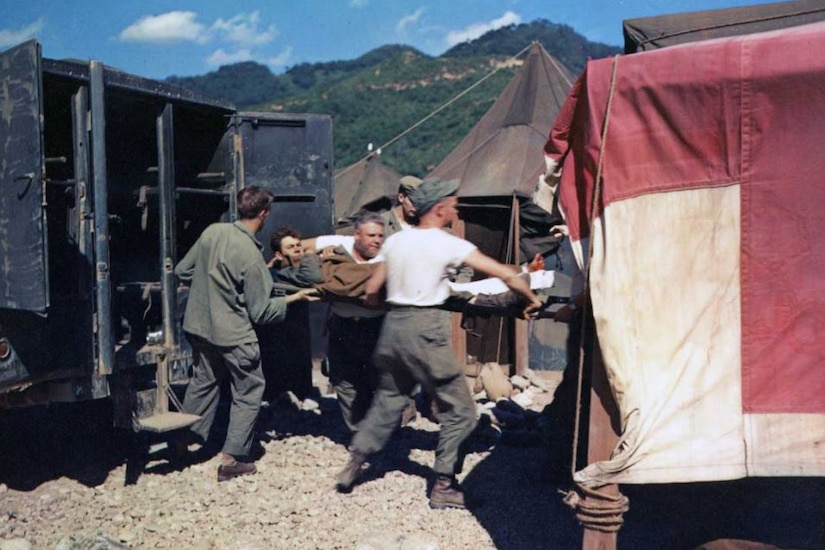 Soldiers move a patient into a tent.