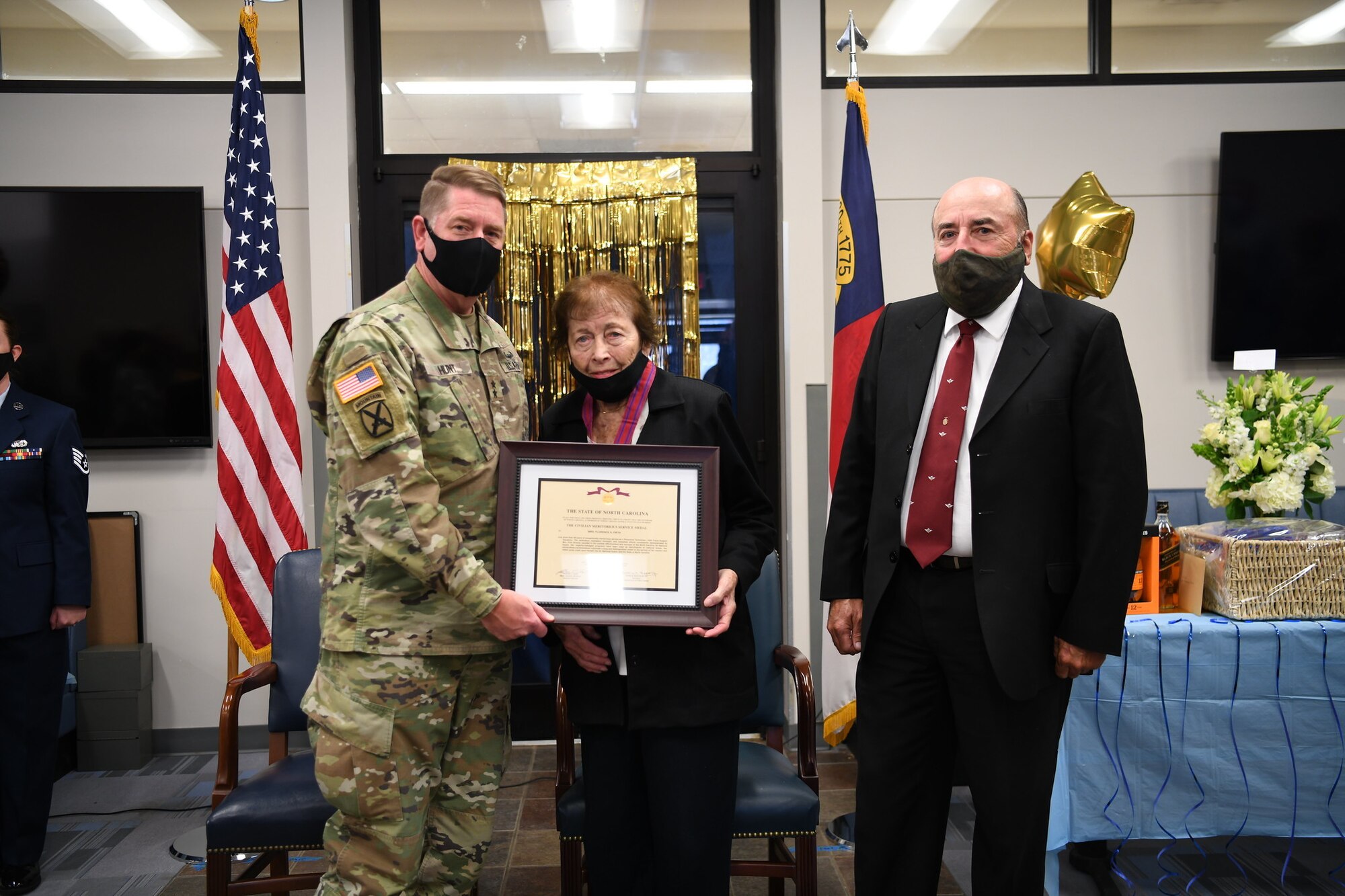 Army Maj. Gen. Todd Hunt (left), the North Carolina National Guard Adjutant General, presents an award certificate to Mrs. Jere Firth (middle) one of the longest employed civilians in the department of defense in recognition of her retirement after over 59 years of service, at the NCANG Base, Charlotte Douglas International Airport, Nov. 19, 2021. Mrs. Firth has worked specifically for the North Carolina Air National Guard since 1972