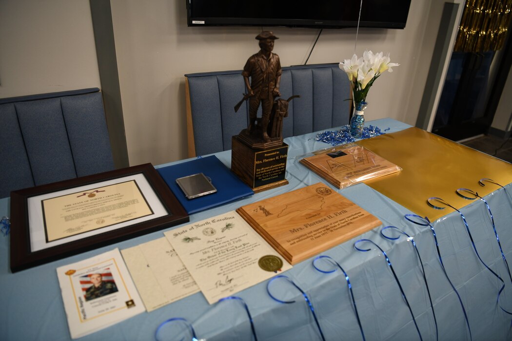 A collection of awards are displayed on a table for presentation to Mrs. Jere Firth, one of the longest employed civilians working for the Department of Defense on the occasion of her retirement after over 59 years of service, at the NCANG Base, Charlotte Douglas International Airport, Nov. 19, 2021. Mrs. Firth has worked specifically for the North Carolina Air National Guard since 1972.