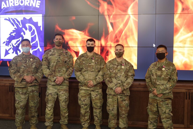 Five service members wear medals for winning a competition.