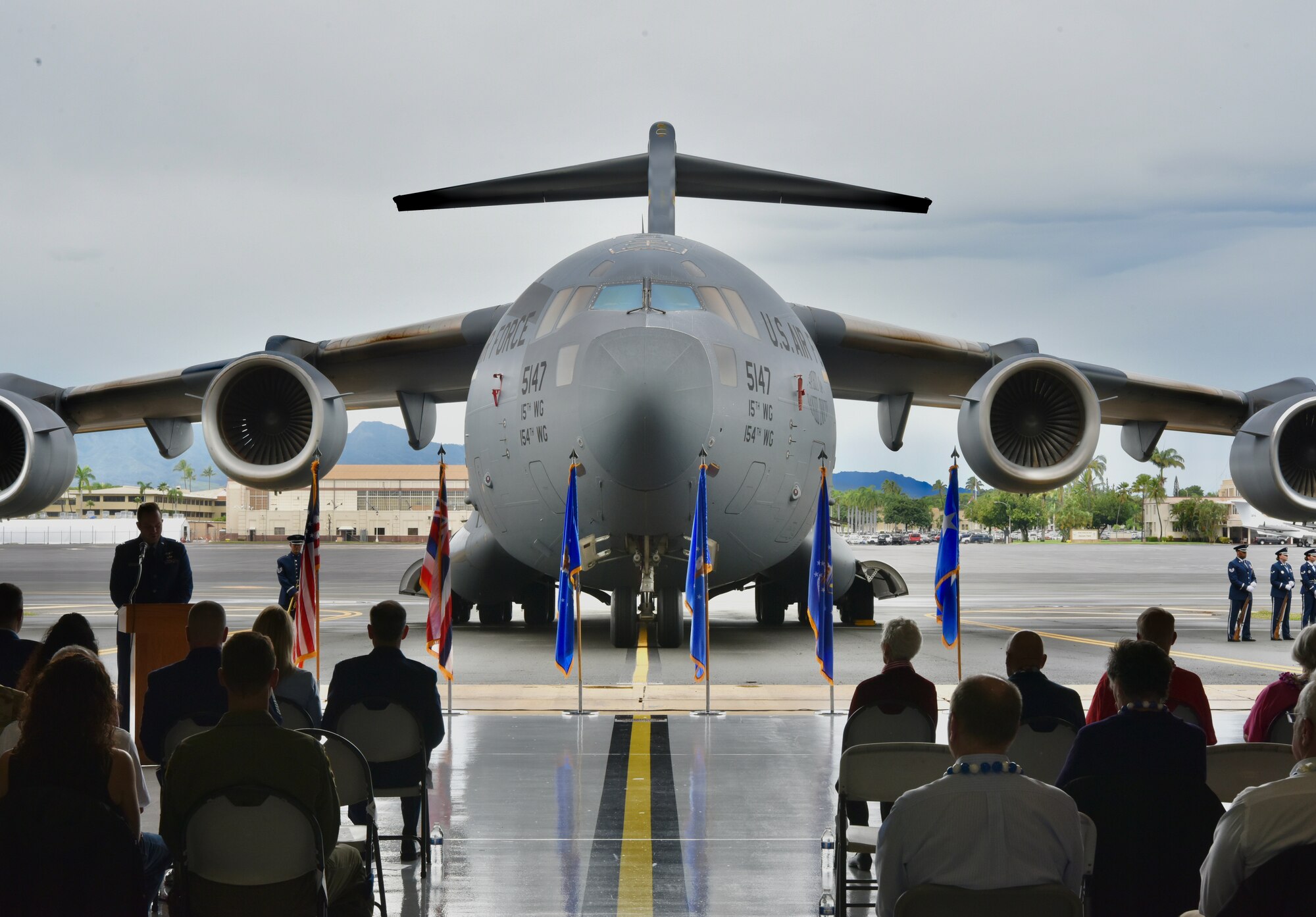 A C-17 Globemaster III static serves as the backdrop to the December 7th Remembrance Ceremony at Joint Base Pearl Harbor-Hickam, Hawaii, Dec. 7, 2021. The event brought together Airmen, Guardians, survivor family members, and more to honor those who gave their lives 80 years ago. (U.S. Air Force photo by 1st Lt. Benjamin Aronson)