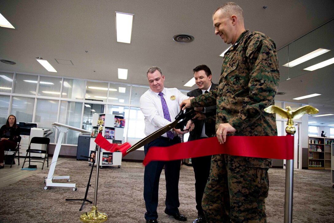 From left to right, Micheal Gieseck, the deputy assistant chief of staff with Marine Corps Community Services, Devin Farmer, the library director for Camp Foster with Marine Corps Community Services, and U.S. Marine Corps Col. Jeffrey L. Hammond, the camp commander of Camps Foster and Lester and commanding officer of Headquarters and Support Battalion, Marine Corps Installations Pacific, cut a ribbon during the grand reopening ceremony for the library on Camp Foster, Okinawa, Japan, Dec. 2, 2021. The ceremony consisted of a ribbon cutting, tour of the renovations, and a performance by the III Marine Expeditionary Force Band. The library showcased renovations with a variety of new education sections and a reorganization of the children and youth area to adhere to a broader range of interests for service members and their families. (U.S. Marine Corps photo by Lance Cpl. Jonathan Beauchamp)