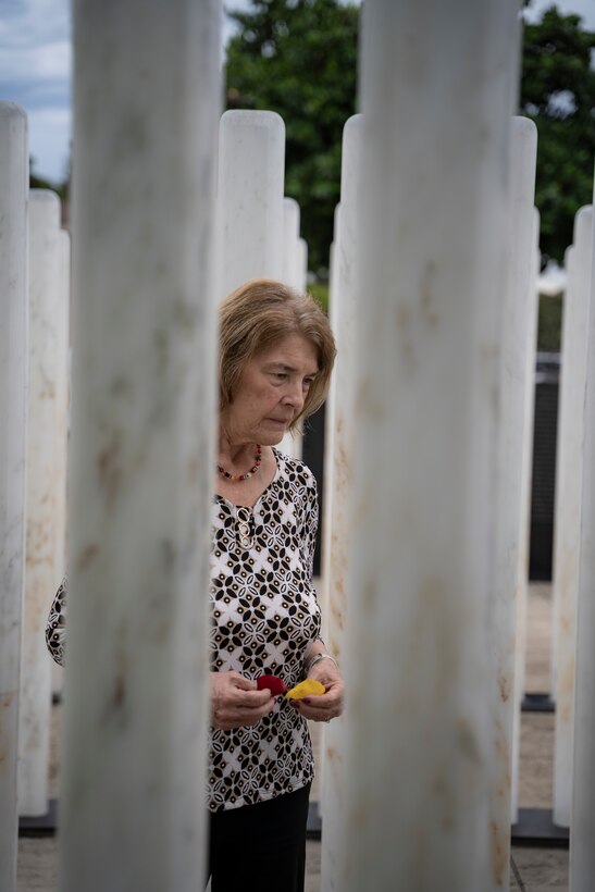 PEARL HARBOR, Hawaii (Dec. 7, 2021) - Carol Sowar waits to lay rose petals at a memorial marker for her uncles, Harold and William Trapp, two Sailors who died when the USS Oklahoma was torpedoed and sunk. Sowar, along with more than 200 visitors paid their respects to the fallen during the 2021 USS Oklahoma (BB-37) Memorial Ceremony which was held on the 80th anniversary of the Japanese attack on Pearl Harbor. Each of the 429 markers represents one Sailor or Marine killed during the attack.  (U.S. Navy Photo by MC1 Jeffrey Hanshaw/Released).