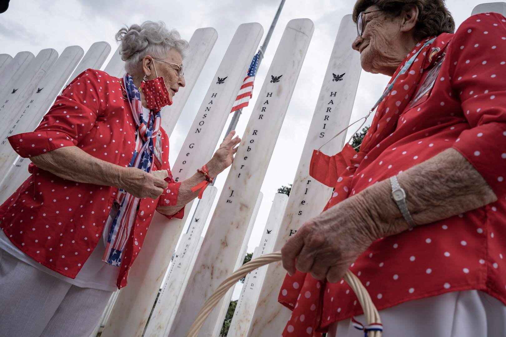 PEARL HARBOR, Hawaii (Dec. 7, 2021) - "Rosie" Mae Krier (left) and "Rosie" Marian Wynn place rose petals at the memorial marker of a close friend at the USS Oklahoma (BB-37) Memorial Ceremony. Wynn was a shipyard worker while Krier built B-17 and B-29 aircraft bombers during WWII. (U.S. Navy Photo by MC1 Jeffrey Hanshaw/Released).