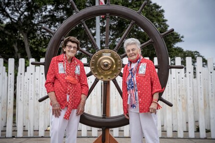 PEARL HARBOR, Hawaii (Dec. 7, 2021) - "Rosie" Marian Wynn (left) and "Rosie" Mae Krier stand before the Helm of the USS Oklahoma (BB-37) on the 80th anniversary of the attack on Pearl Harbor when 429 Sailors and Marines on board lost their lives. Wynn was a shipyard worker while Krier built B-17 and B-29 aircraft bombers during the war. (U.S. Navy Photo by MC1 Jeffrey Hanshaw/Released).