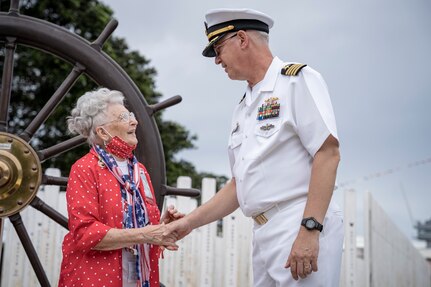 PEARL HARBOR, Hawaii (Dec. 7, 2021) - "Rosie" Mae Krier meets with Pearl Harbor Naval Shipyard and Intermediate Facility Commander Capt. Richard Jones in front of the USS Oklahoma Memorial and helm during the 80th anniversary of the attack on Pearl Harbor when 429 Sailors and Marines on board lost their lives. Krier built B-17s and B-29s during the war. (U.S. Navy Photo by MC1 Jeffrey Hanshaw/Released).