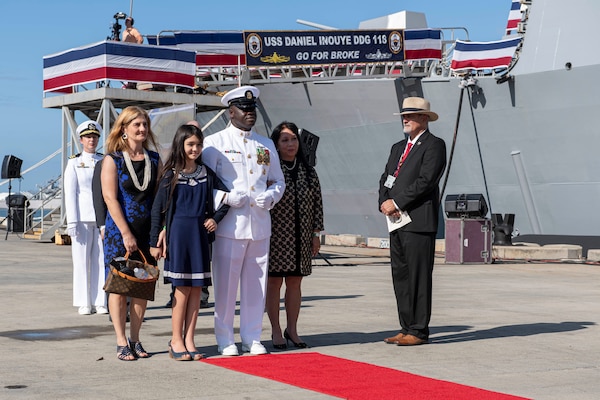 PEARL HARBOR, Hawaii (Dec. 8, 2021) Command Master Chief Simeon Yeboah escorts Matrons of Honor Jessica Carroll Inouye, left, Jennifer Goto Sabas, right, and 11-year-old Maid of Honor Maggie Inouye, during the commissioning ceremony of USS Daniel Inouye (DDG 118). Homeported at Joint Base Pearl Harbor-Hickam, DDG 118 is the first U.S. Navy warship to honor the Honorable Daniel K. Inouye, a U.S. senator from Hawaii who served from 1962 until his death in 2012. During World War II, Inouye served in the U.S. Army’s 442nd Regimental Combat Team, one of the most decorated military units in U.S. history. For his combat heroism, which cost him his right arm, Inouye was awarded the Medal of Honor. (U.S. Navy photo by Mass Communication Specialist 1st Class Kelby Sanders)