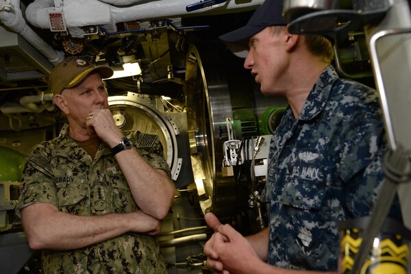 Men wearing military uniforms hold a discussion.