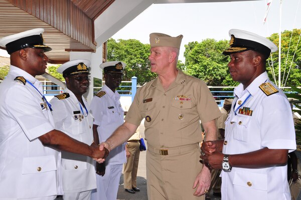 Men in navy uniforms shake hands.