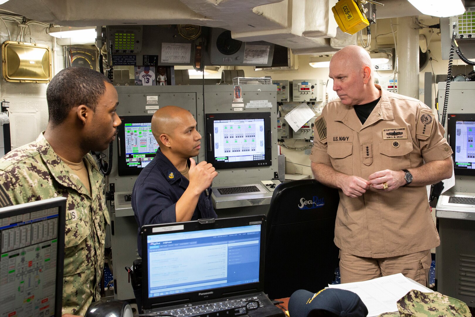 A senior naval officer speaks with sailors.