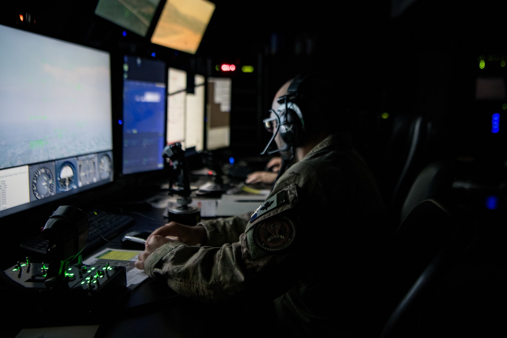 man seated in front of computer screen controls a simulated aircraft