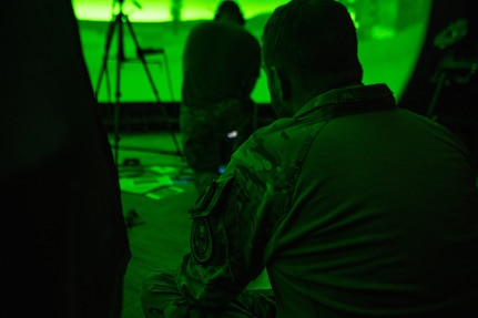 man is lit in green while seated in a simulator