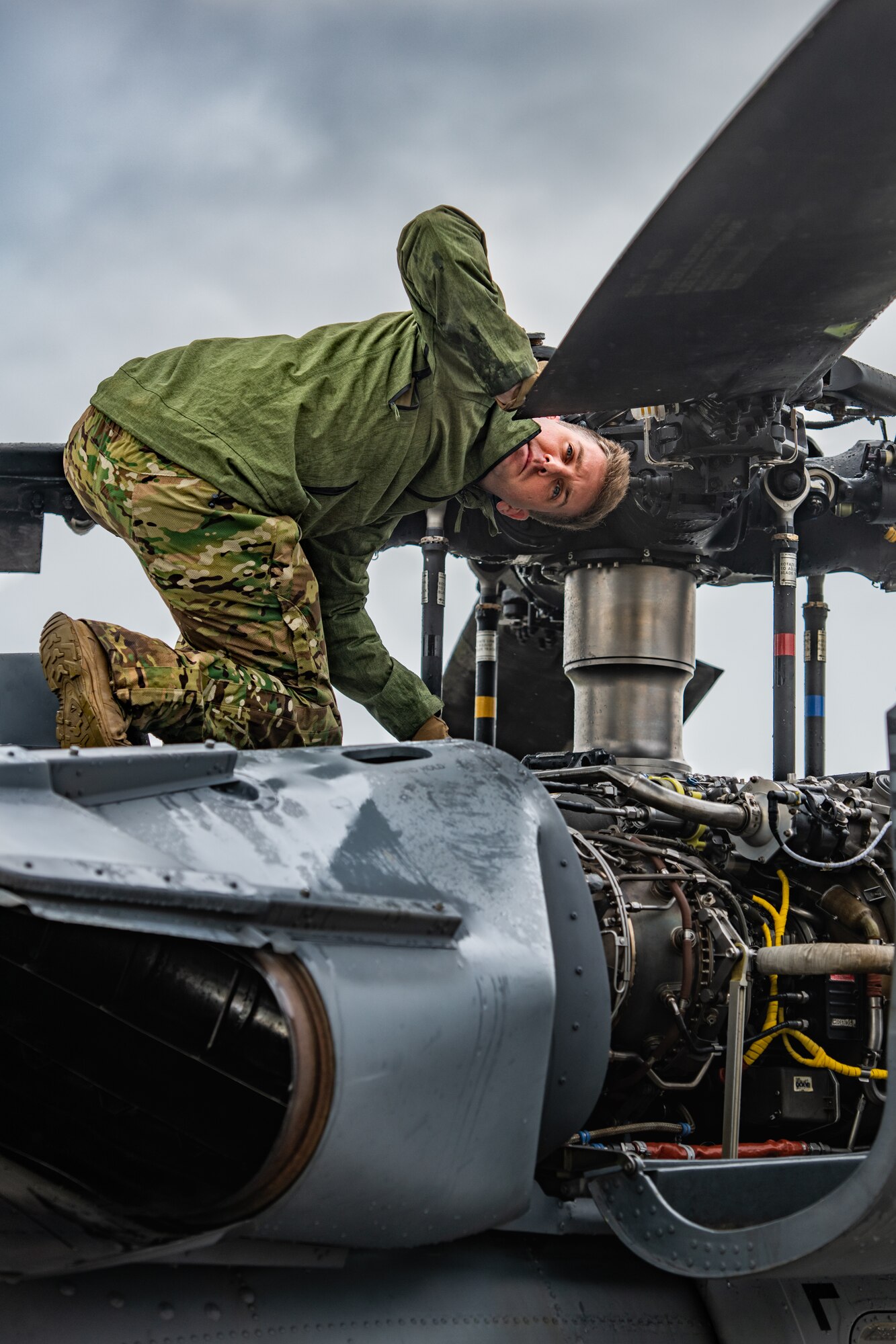 A U.S. Air Force member checks the main rotor of a helicopter