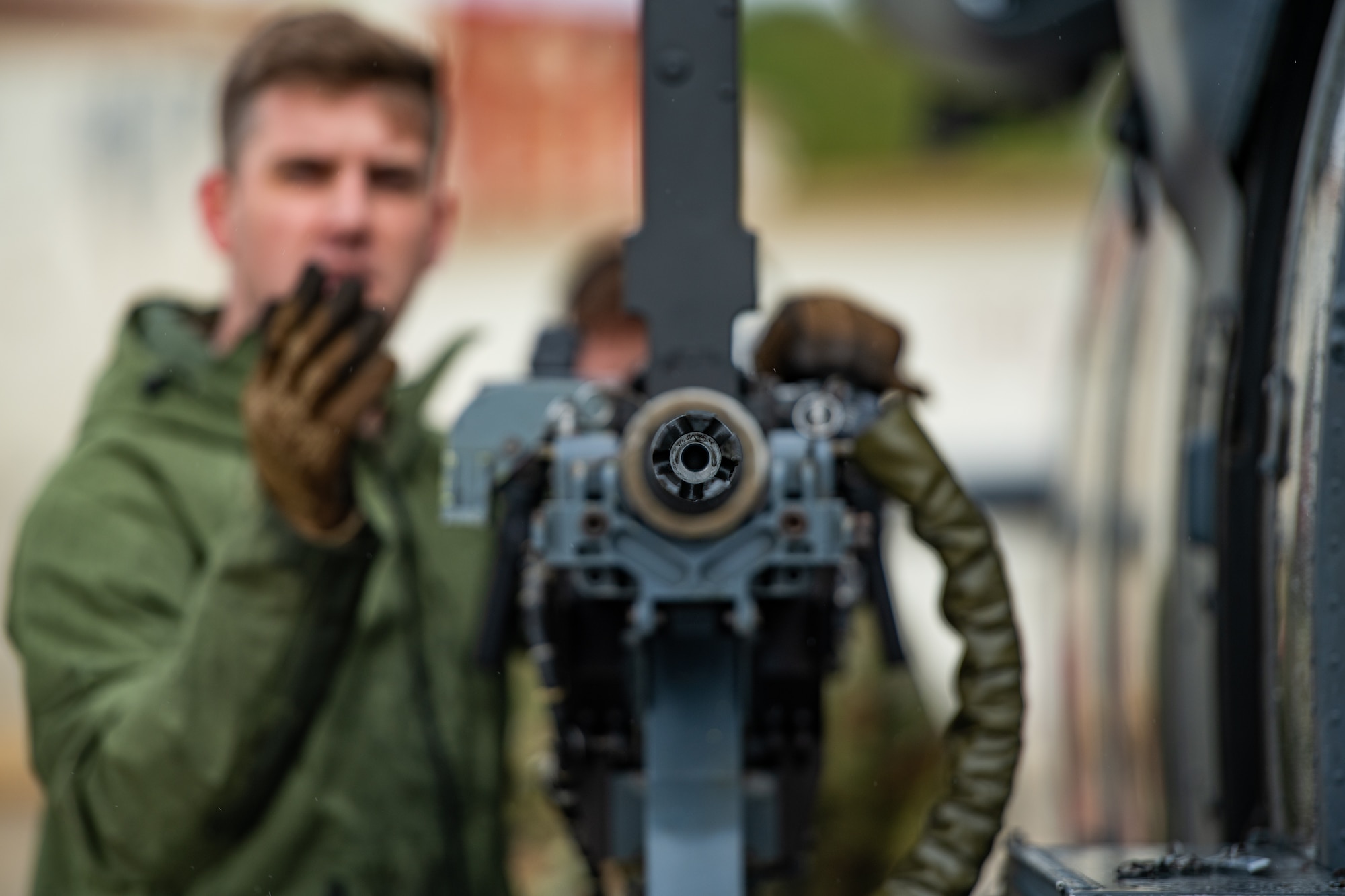 A U.S. Air Force member checks the gun on the side of a helicopter