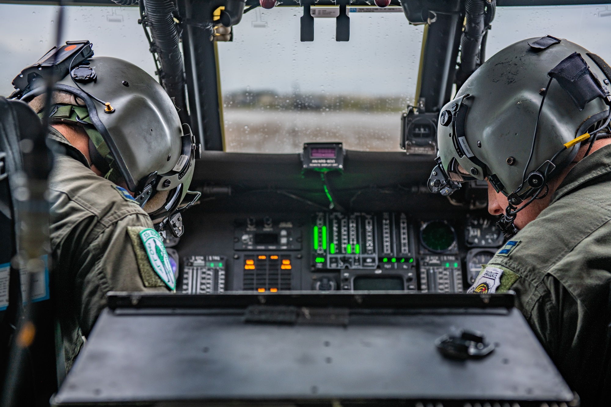 Two helicopter pilots work the communications systems for a helicopter