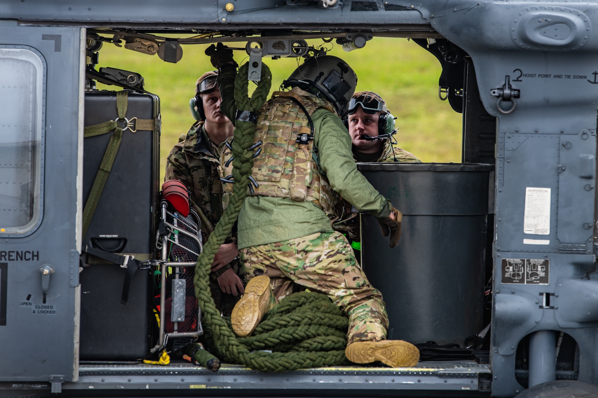 Three U.S. Air Force members prepare a helicopter for flight