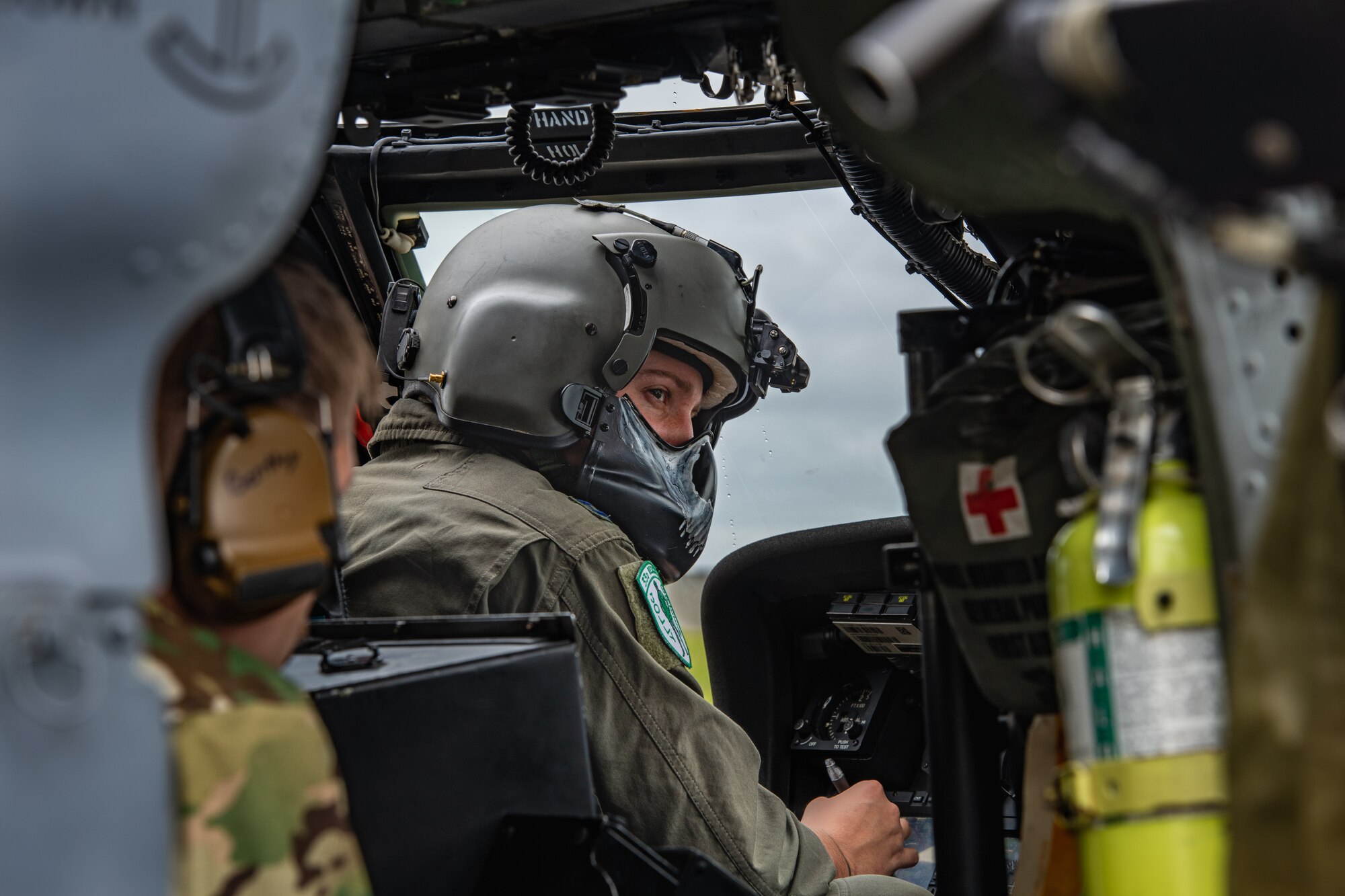 A helicopter pilot looks to his right as he converses with his copilot.