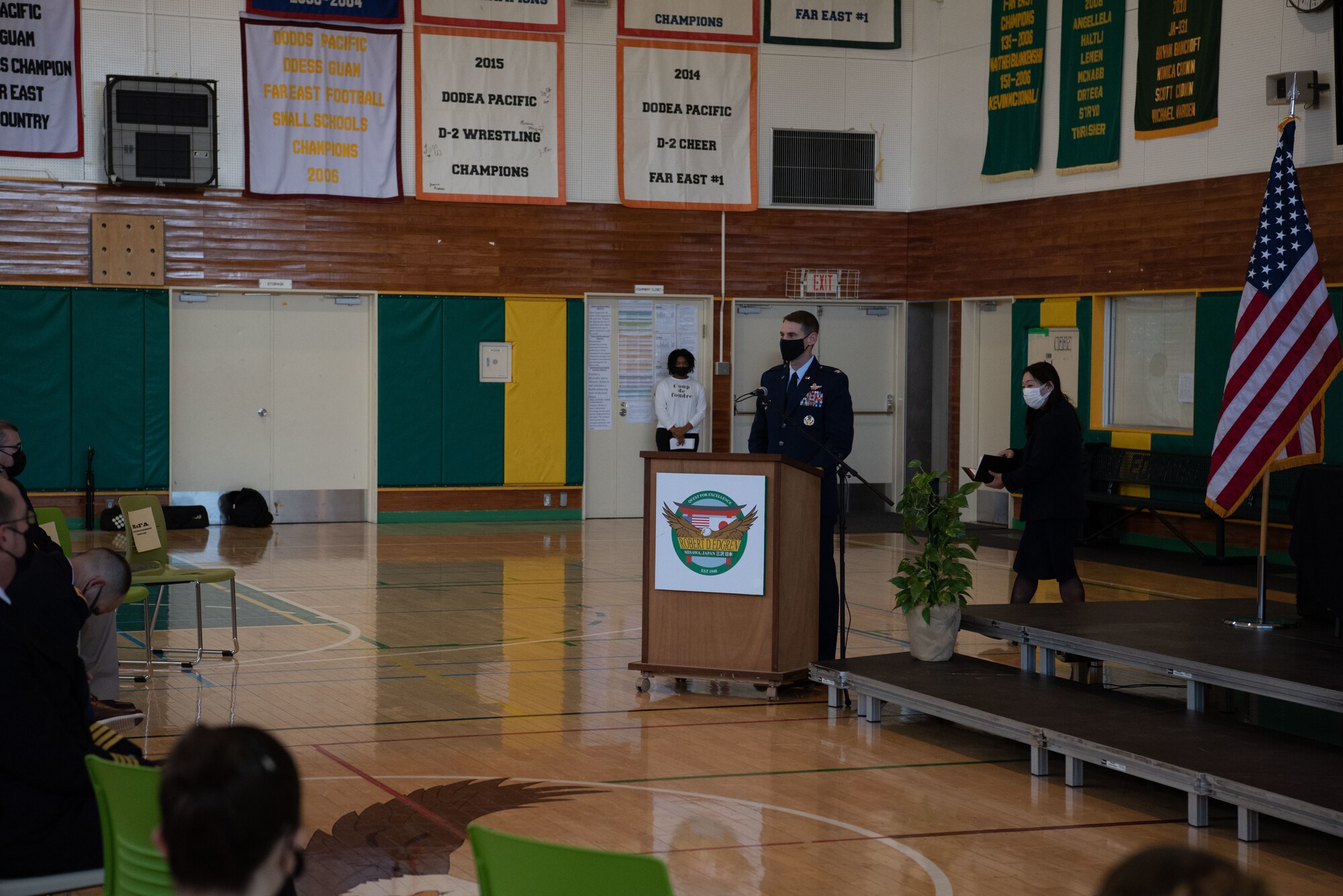 A military member speaks in front of a podium.