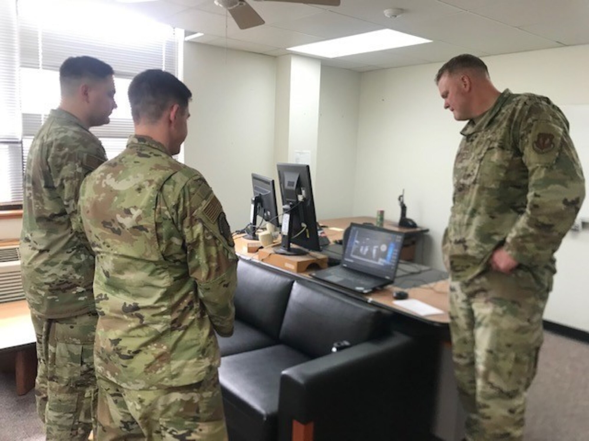 Three military members standing in an office.