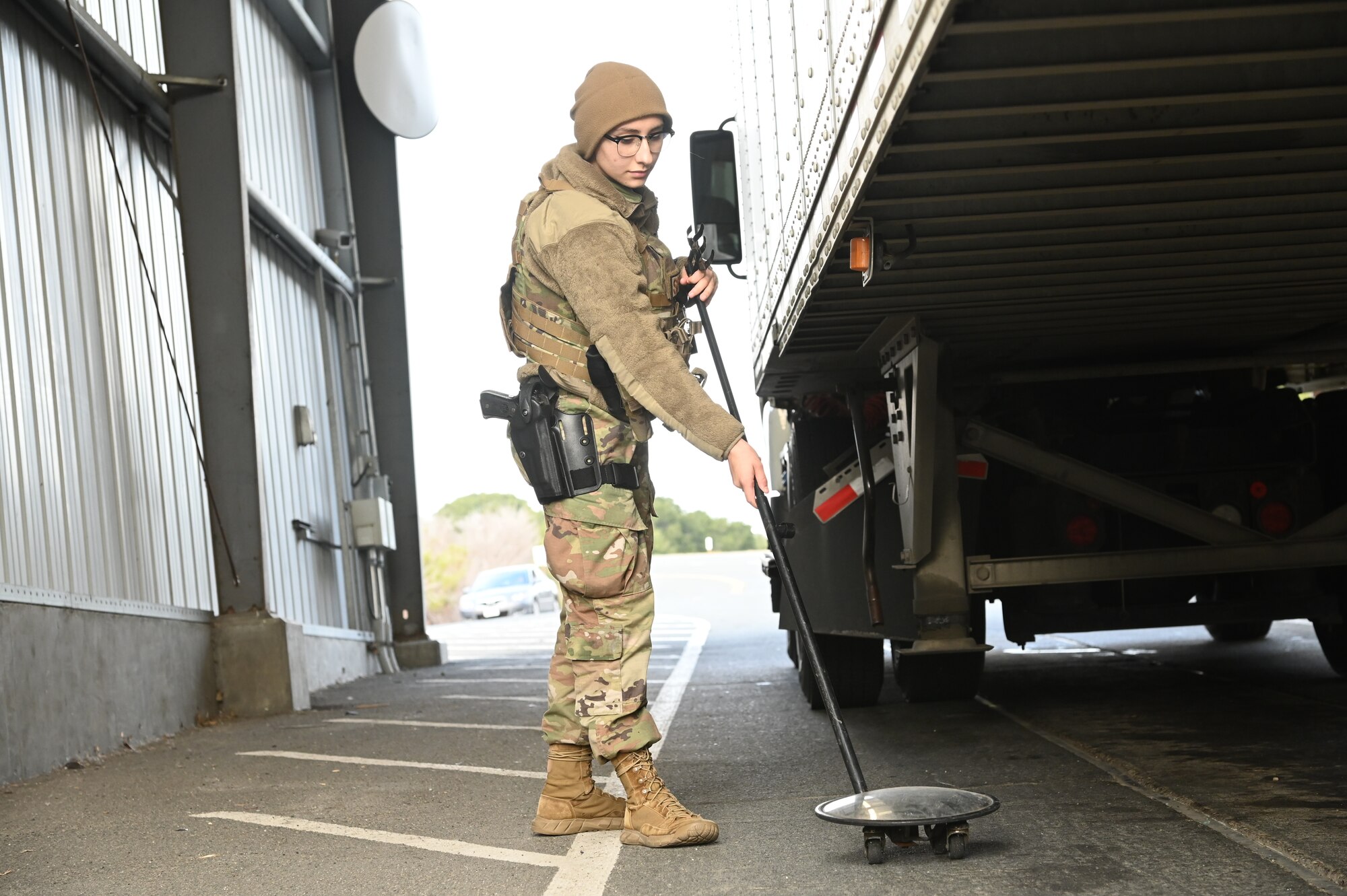 Airman 1st Class Alexis Abeyata, Space Launch Delta 30 installation entry controller, checks the under carriage of a vehicle during a routine inspection. Abeyata does an all-around commercial vehicle check with a mirror at Vandenberg Space Force Base, Calif., Dec. 7, 2021. (U.S. Space Force photo by Airman 1st Class Rocio Romo)