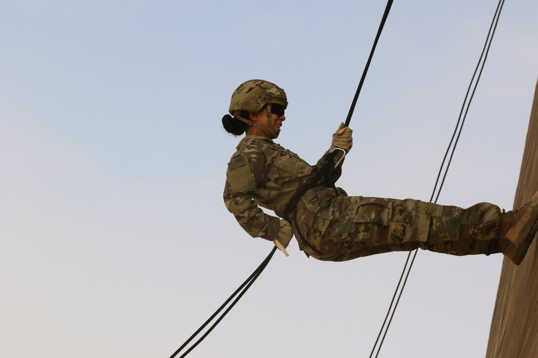 A soldier rappels down a tower.