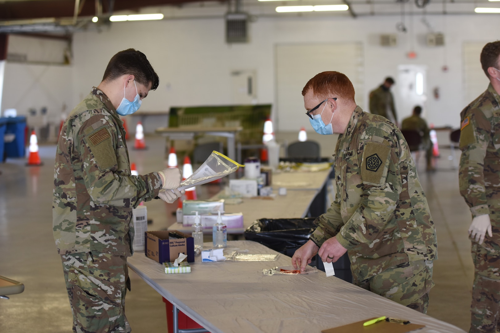 U.S. Army Sgt. Alec Broughton and U.S. Air Force Senior Airman Nicholas Hensley process a nasal test swab from an individual tested for COVID-19 at the McLean County Fair Grounds test site in Bloomington, Ill., April 21, 2020.  Individuals perform the nasal test on themselves and then transfer the test kit to workers at the site without any contact, which eliminates much of the personal protection equipment that previously had to be worn.  (U.S. Air National Guard photo by Tech Sgt. Andrew Kleiser)