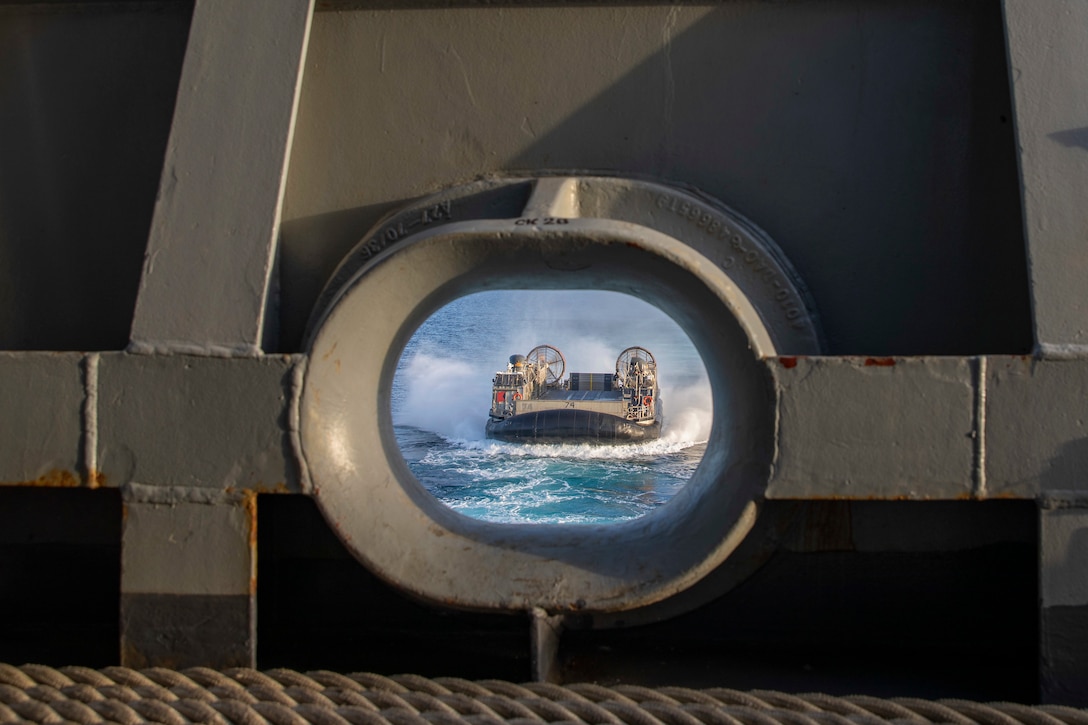 A landing craft is seen approaching a ship through a porthole.