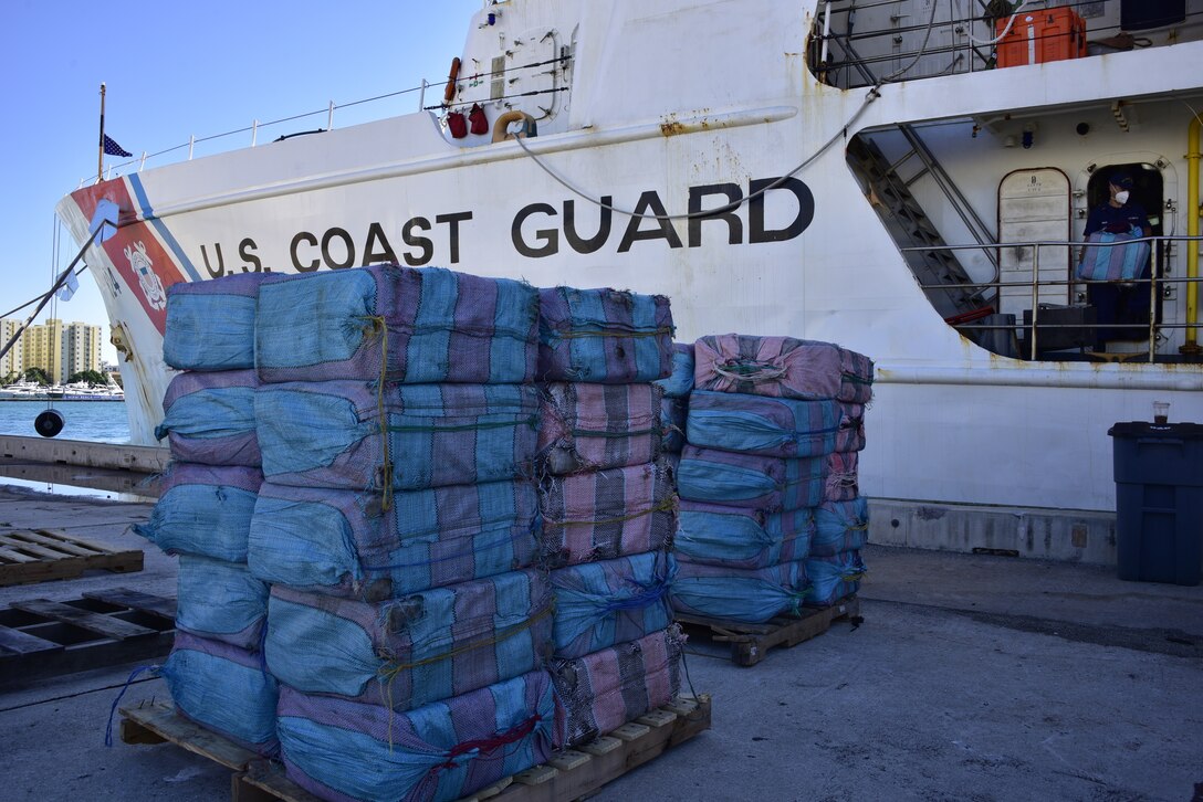 Bales of contraband are stacked in front of the Coast Guard Cutter Dauntless (WMEC-624) at Base Miami Beach, Dec. 7, 2021.