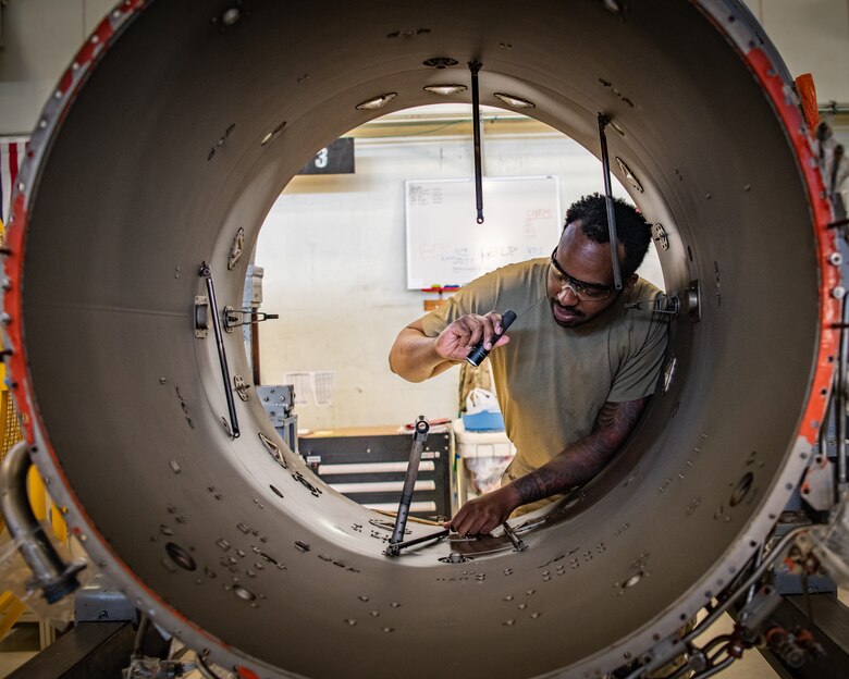 An Airman inspects a fan duct on an engine.