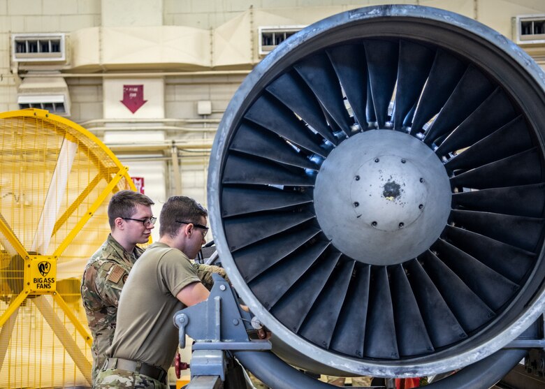 Two Airmen work on an engine.