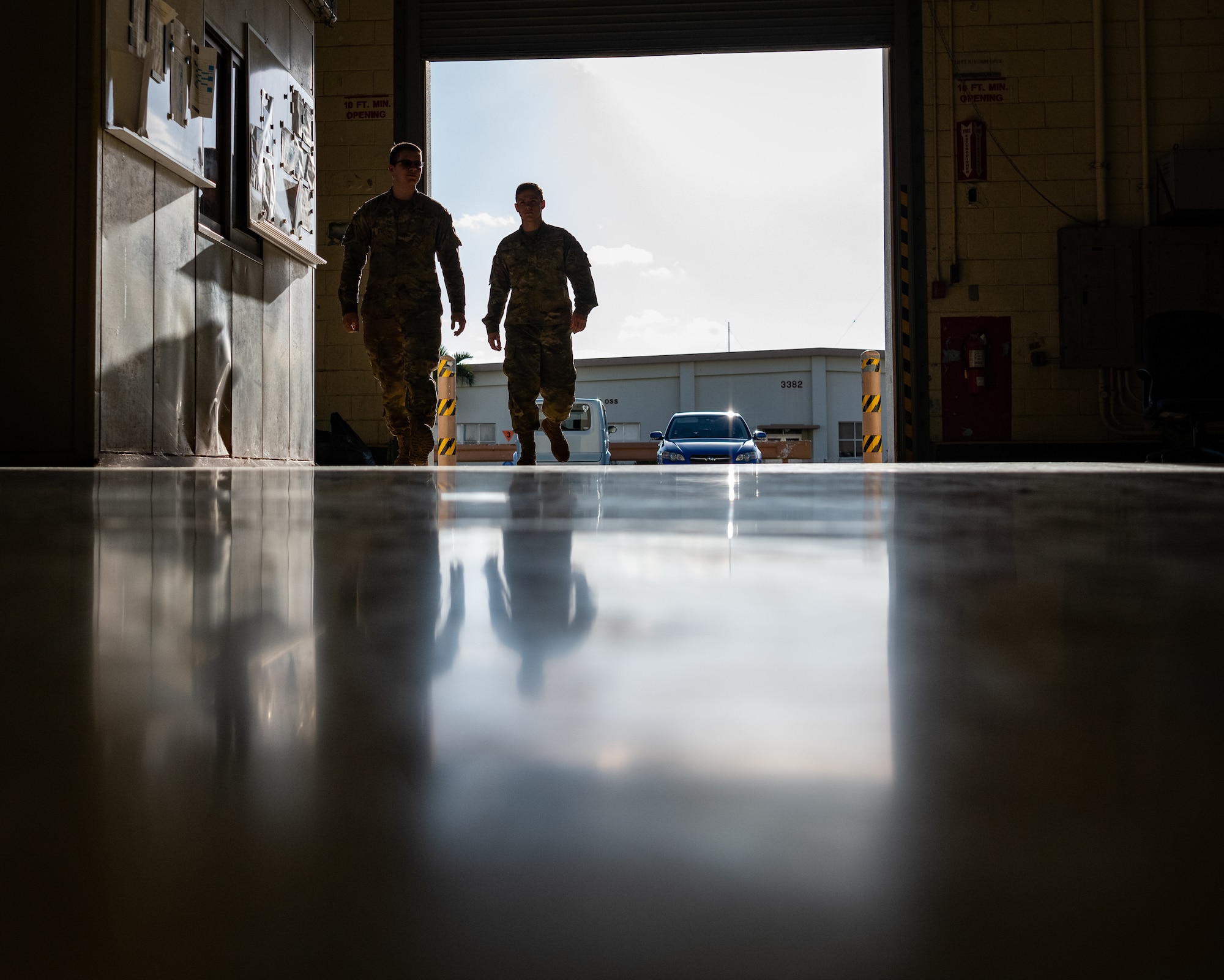 Two Airmen walk into a hangar.