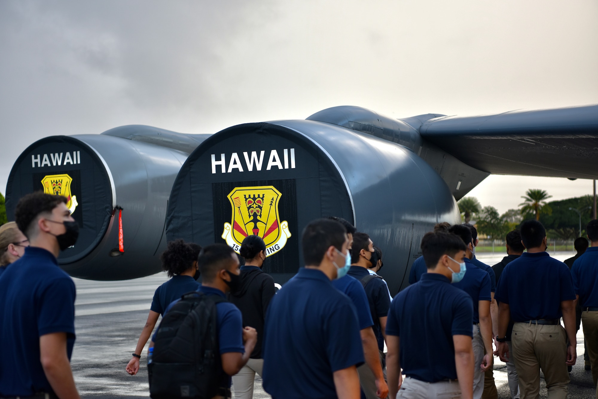 Cadets from the University of Hawaii Air Force Reserve Officer Training Corps walk past engine covers of a KC-135 Stratotanker during a base tour at Joint Base Pearl Harbor-Hickam, Hawaii, Dec. 3, 2021. Cadets met with officers and went aboard two static aircraft to learn more about the operational Air Force and active duty life. (U.S. Air Force photo by 1st Lt. Benjamin Aronson)