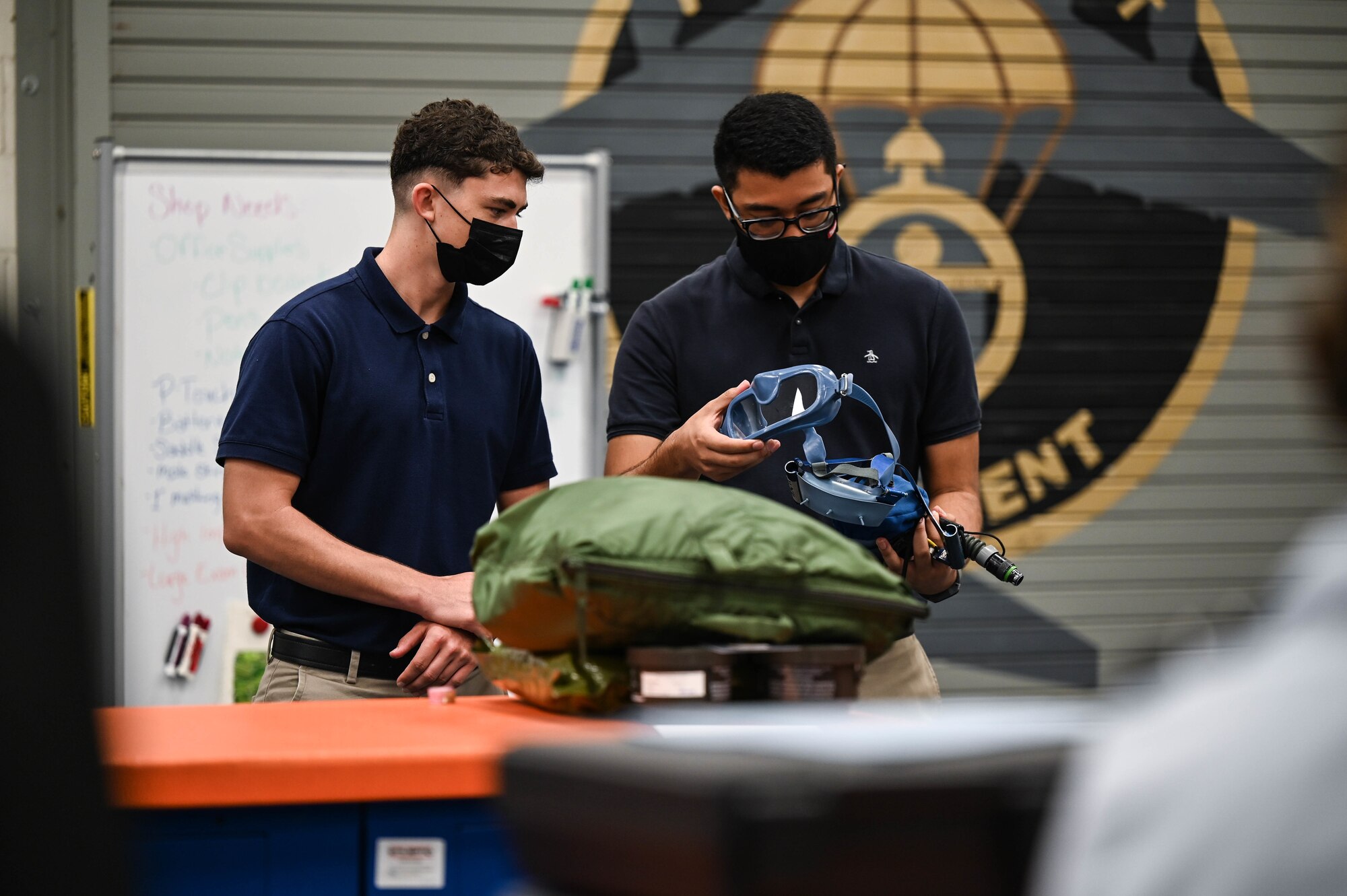 Kobie Moody and Kalani Herrera, University of Hawaii Air Force Reserve Officer Training Corps cadets, observe a quick-don mask used in a C-17 Globemaster III during a base tour at Joint Base Pearl Harbor-Hickam, Hawaii, Dec. 3, 2021. Airmen assigned to the 15th Operations Support Squadron aircrew flight equipment section highlighted their shop’s mission and demonstrated equipment used in flight during C-17 operations. (U.S. Air Force photo by Staff Sgt. Alan Ricker)