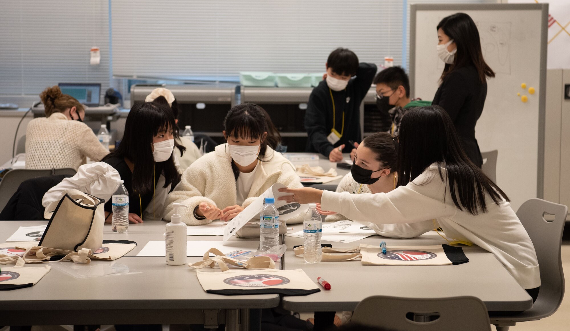Students gather around the table to work on a project.