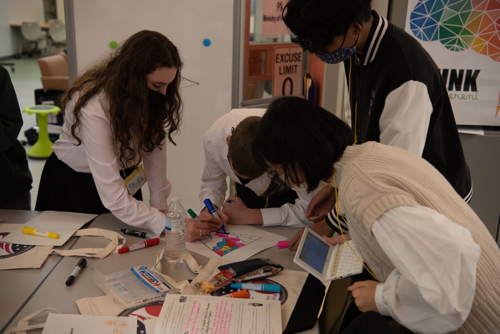 Students circle a table working on their project.