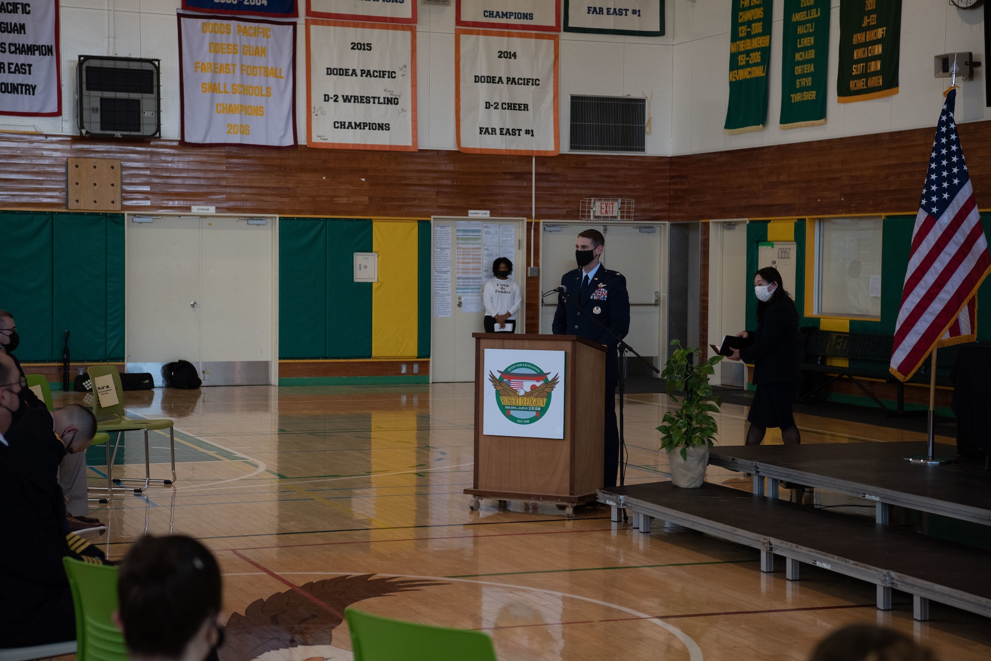 A military member speaks in front of a podium.