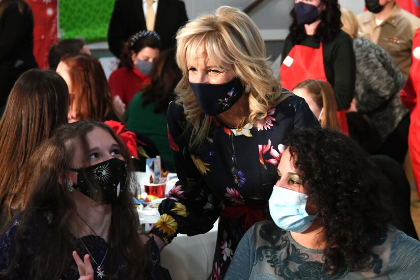 First Lady Dr. Jill Biden speaks people at a holiday gathering.