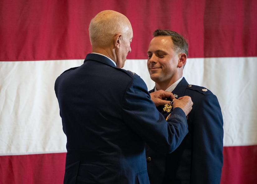 A man affixes a medal to an airman's uniform.