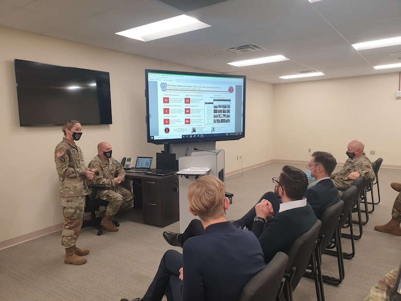 U.S. Army National Guard Maj. Christine Pierce (standing), Team Chief for the Pennsylvania Army National Guard’s Defensive Cyber Operations Element, briefs Lithuanian cyber defense representatives at Biddle Air National Guard Base in Horsham, Pennsylvania on December 6, 2021, about the DCOE Team mission and recent engagements with Pennsylvania’s State Partnership Program partner Lithuania.