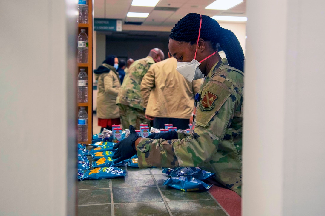 An airman wearing a face mask prepares snacks.