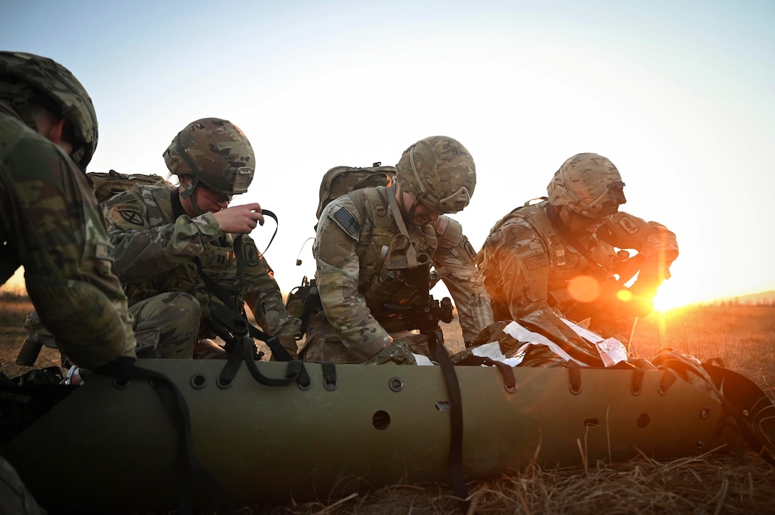 Soldiers perform care on a simulated patient in a field.